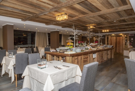 Ristorante spazioso con tavoli bianchi, bar in legno, decorazioni di frutta e luci a sospensione a forma di numero "7".