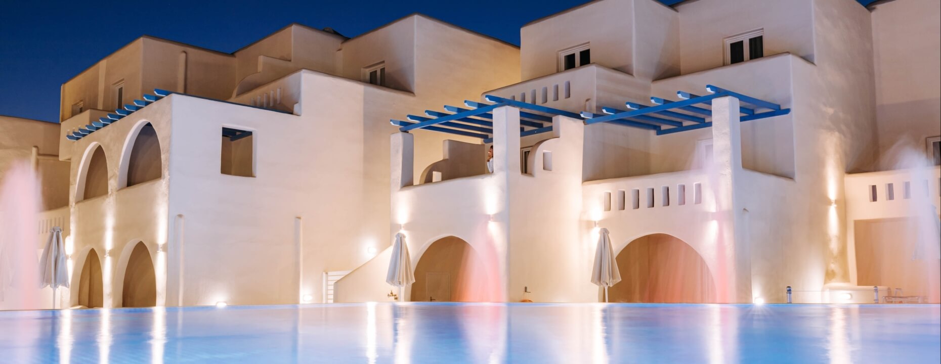 Serene pool scene with light blue waters, white building, blue accents, and soft lighting, evoking luxury and tranquility.