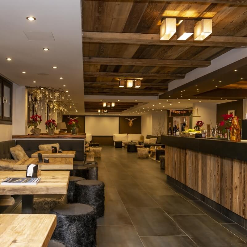 Modern rustic restaurant interior with wood beams, cozy booths, large blackboard, and warm lighting creating an inviting atmosphere.