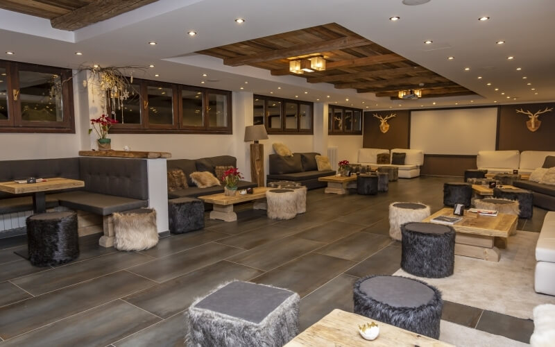 Una stanza spaziosa con arredi rustici moderni, divani accoglienti, tavoli in legno e decorazioni come teste di cervo.