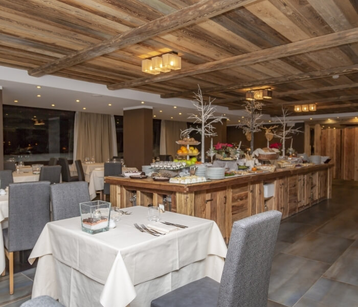 Dining area with a buffet table, festive decor, white tablecloths, and a warm ambiance, suggesting a holiday event.