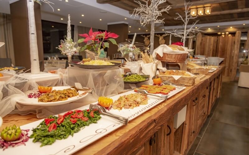 Lavish buffet with salads, roast chicken, and festive decor in a warm restaurant setting, ideal for Christmas celebrations.