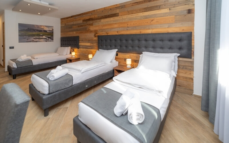 Hotel room with two single beds, gray headboards, white linens, wood paneling, and a modern, clean atmosphere.