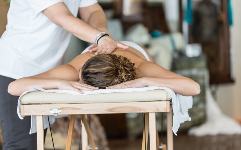 Una donna riceve un massaggio su un tavolo di legno, circondata da un'atmosfera calma e professionale in una spa.