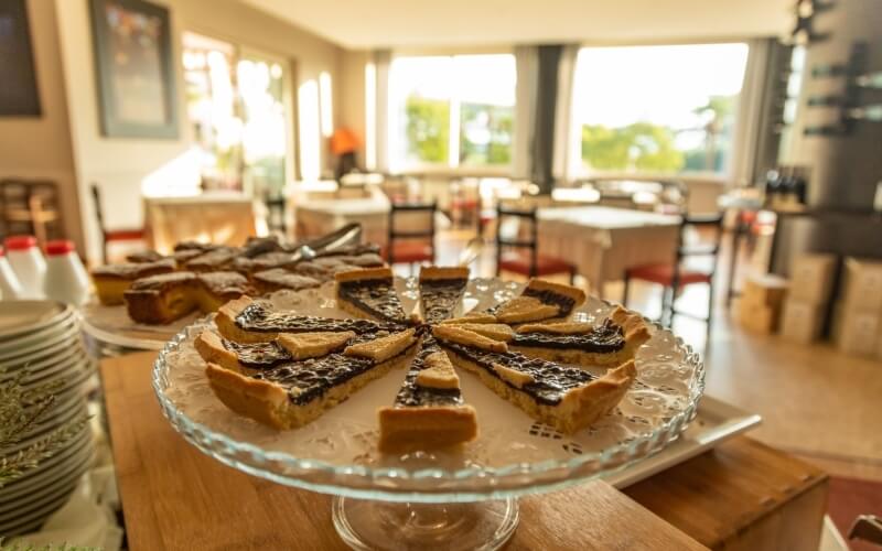 Delicious pie on a glass cake stand, surrounded by additional pies and plates, in a warm, inviting bakery setting.