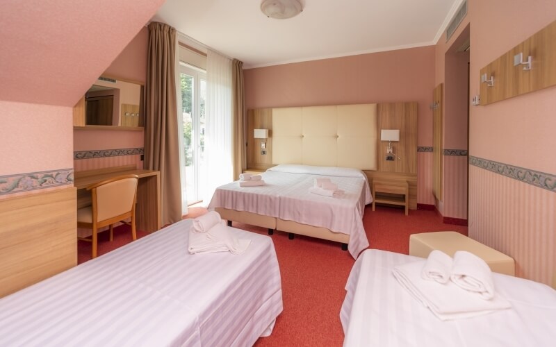 Spacious hotel room with two beds, warm colors, natural light, and cozy furnishings, inviting relaxation and comfort.