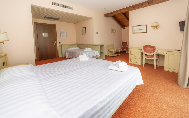 Hotel room with two neatly made beds, a desk with a chair, light orange walls, and an inviting ambiance.