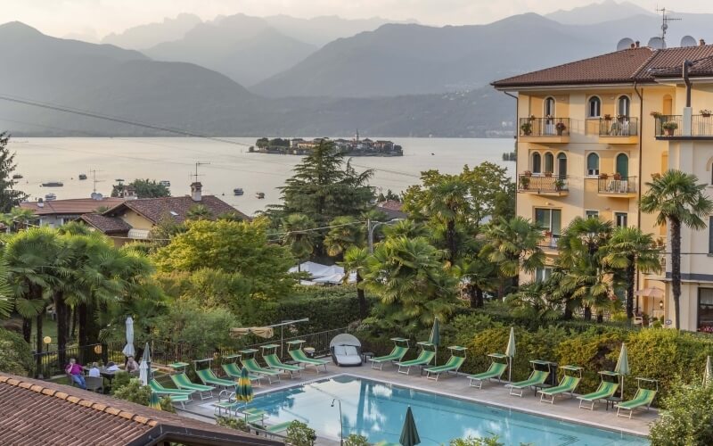 Serene pool scene with lounge chairs, trees, and mountains in the background, suggesting a peaceful vacation atmosphere.