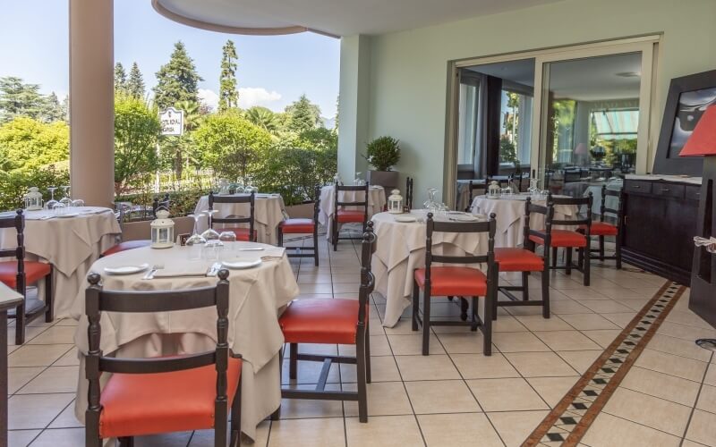 Outdoor dining area at Falcony Cafe with tables, white tablecloths, and a view of trees under a clear blue sky.