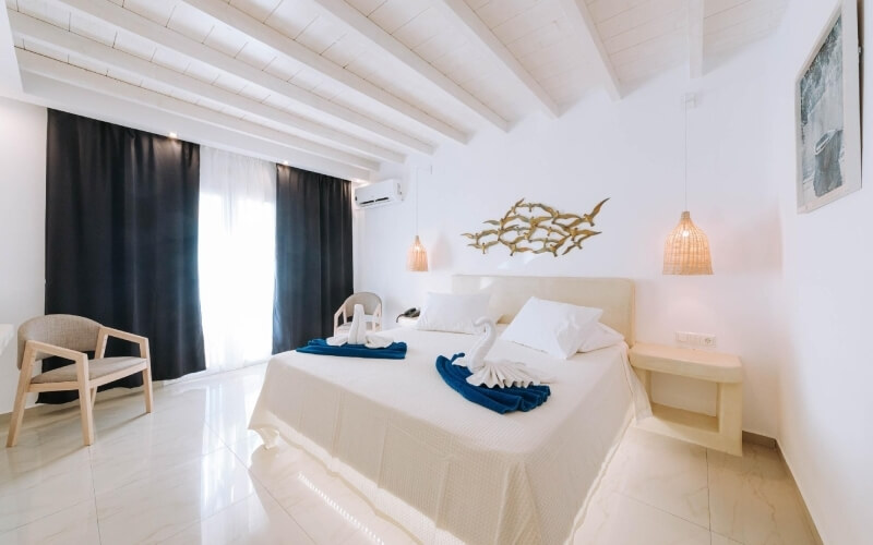 Camera serena con letto bianco, asciugamani a forma di cigno, pareti bianche e decorazioni eleganti.