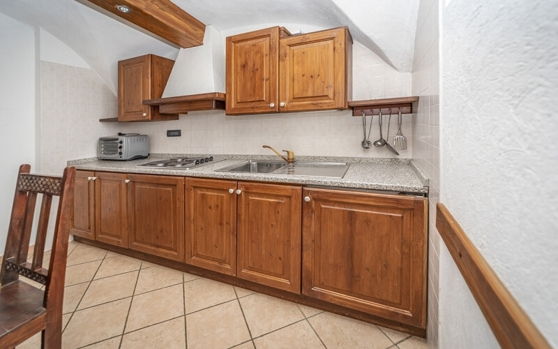 Cozy kitchen with wooden cabinets, granite countertops, stainless steel appliances, and a corner wooden chair.