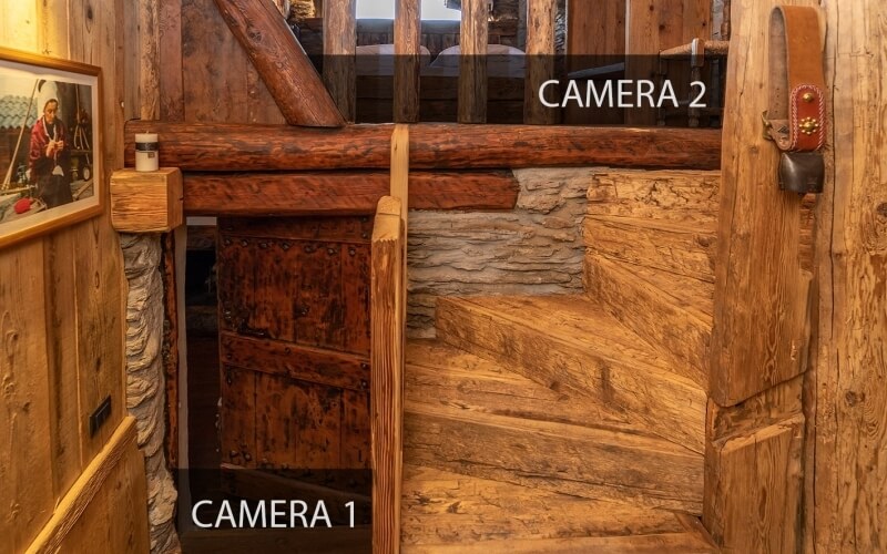 Rustic wooden staircase with stone wall, framed photo of man with skis, and decorative ski-like objects on the wall.