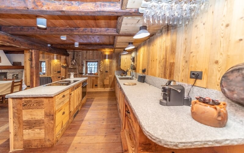 Rustic kitchen in a wooden cabin with granite countertops, appliances, and a cozy ambiance, perfect for cooking and socializing.