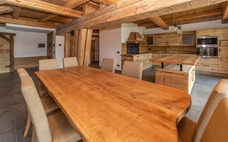 Spacious rustic kitchen and dining area with wooden beams, light cabinets, a large island, and a warm inviting ambiance.