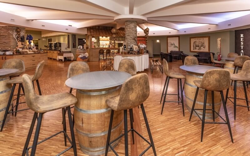 Large, well-lit bar area with green and wood-paneled walls, curved counter, artwork, and rustic seating in a casual setting.