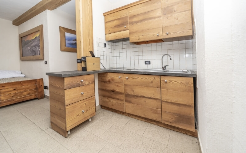 Cucina con armadi in legno chiaro e letto in camera da letto, atmosfera pulita e organizzata.