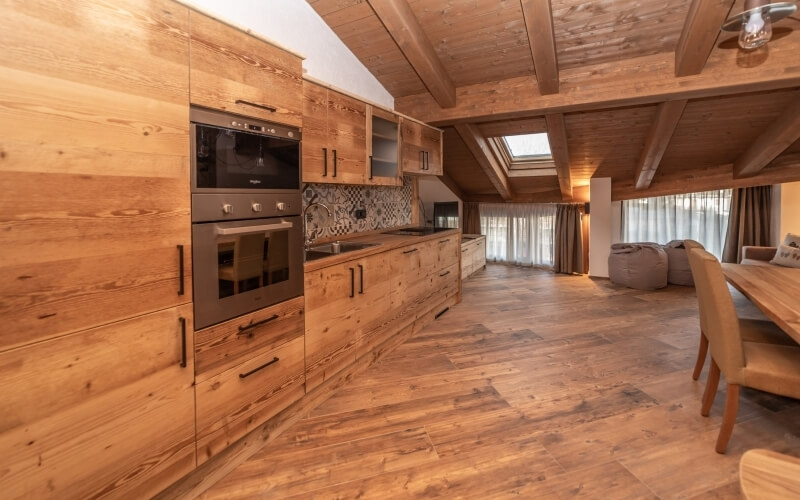 Spacious open-plan kitchen and living area with wooden accents, large windows, and a cozy dining and seating arrangement.