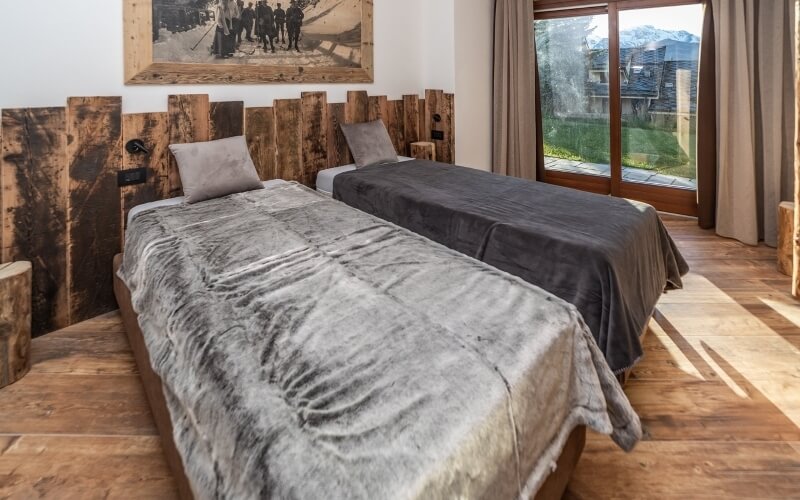 Cozy room with two single beds, a mountain view window, and a framed picture of people in front of mountains.