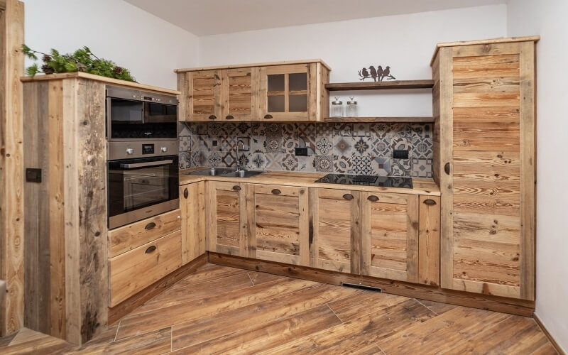 Modern kitchen with rustic wooden cabinets, dark countertops, decorative backsplash, and open shelving, exuding warmth and sophistication.
