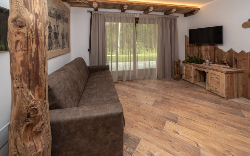 Rustic living room with a brown couch, sheer curtains, wooden walls, and a cozy atmosphere featuring earthy tones.