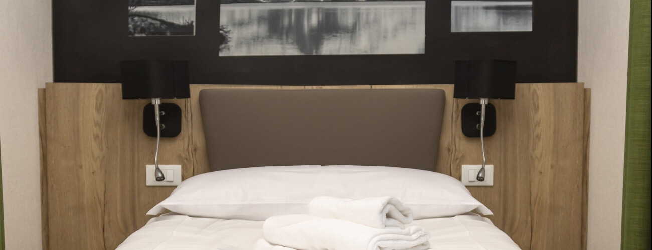 Camera da letto serena con letto, biancheria bianca, lampade nere, opere d'arte in bianco e nero e pannelli verdi.