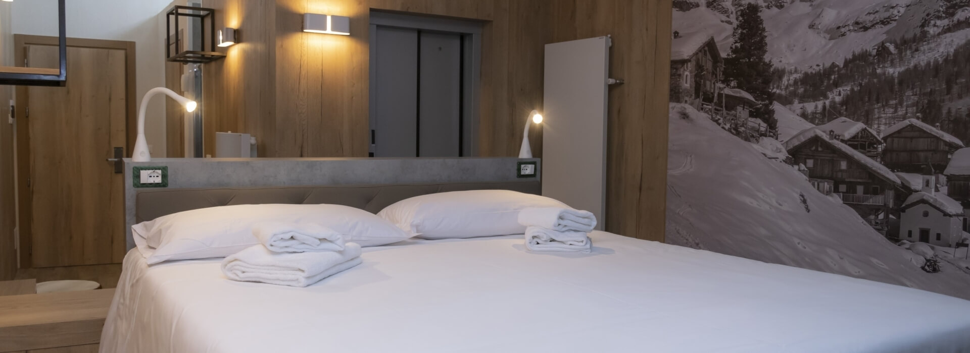 Camera serena con letto bianco, fotografia in bianco e nero, scaffale metallico e porte scorrevoli grigie.