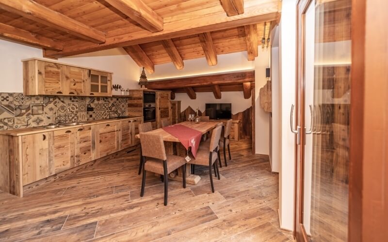 Rustic kitchen and dining area with wooden accents, light cabinets, a wooden table, and a cozy ambiance.