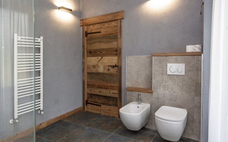 Modern bathroom featuring a white toilet, bidet, and sink, emphasizing minimalism and elegance with clean lines and natural materials.