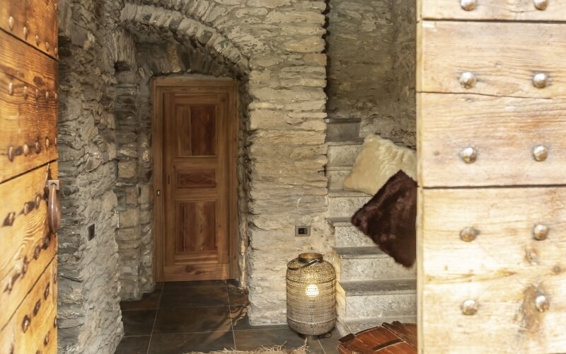 A dimly lit room with stone walls, a wooden door at the far end, and a decorative lantern in the foreground.