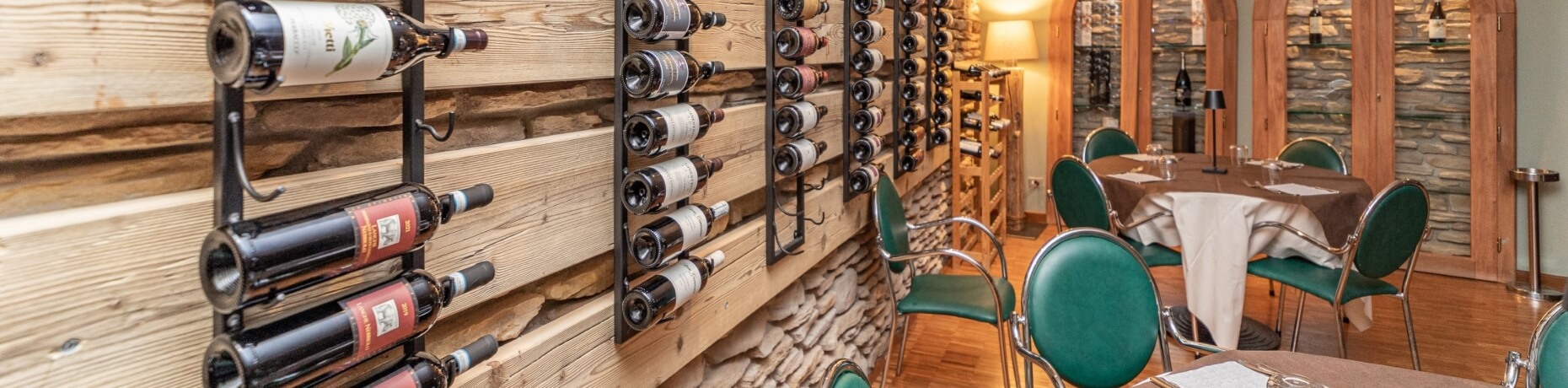 Cozy restaurant dining area with a wine wall, a table set for guests, and warm lighting.