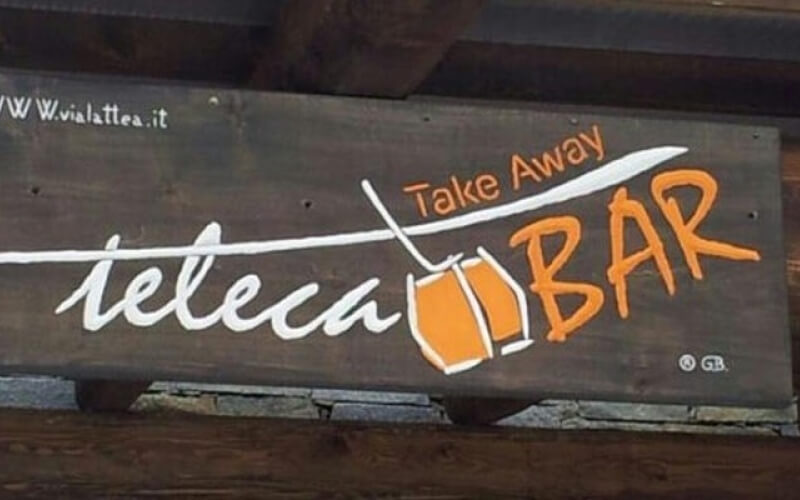 Sign for "Teleca" restaurant/bar with a wooden background, featuring a glass illustration, "Take Away," and "BAR" text.