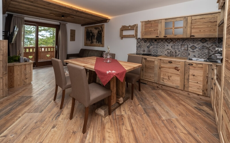 A cozy dining nook with a brown sofa, wooden cabinets, and a vibrant table setting in a rustic-modern room.