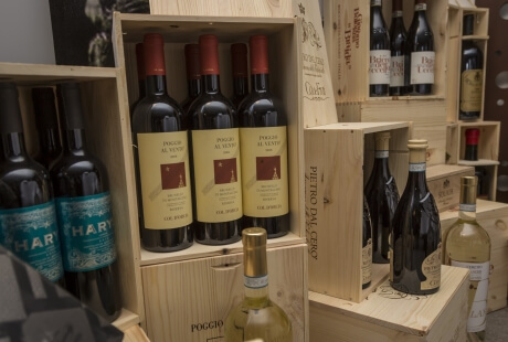 A collection of dark wine bottles in wooden crates, with a black-and-white photo and a brown wall with circular objects in the background.