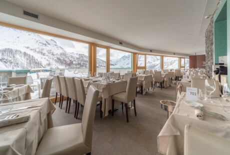 Elegant dining room with mountain views, minimalist decor, white table settings, and a tranquil atmosphere.