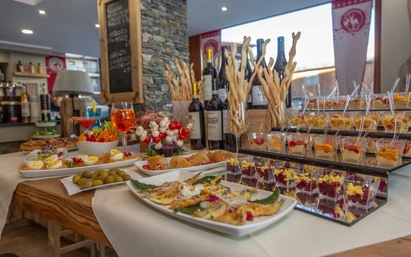 A table with assorted food and drinks, set in a restaurant with a stone wall and shelves of alcohol in the background.