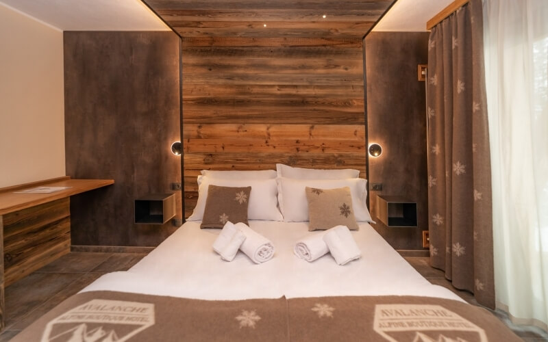 Serene bedroom with wooden headboard, white linens, taupe accents, and snowflake-patterned decor, exuding tranquility.