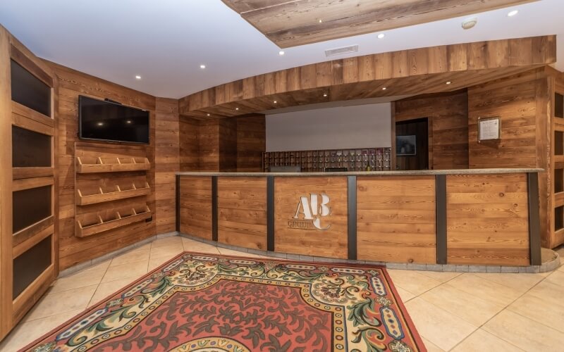 Interior of a room with a wooden front desk, shelves, a TV, and a dark doorway, suggesting possible storage for beverages.