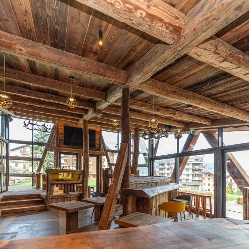 Interno in legno con tavoli, bar, luci e vista panoramica.