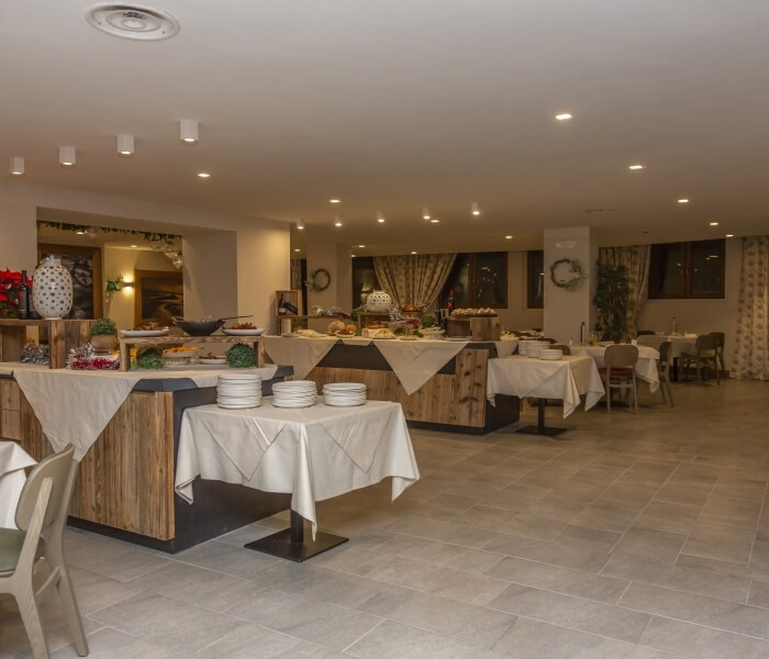 Large, festive dining area with rows of tables, white tablecloths, and a Christmas tree visible through the window.