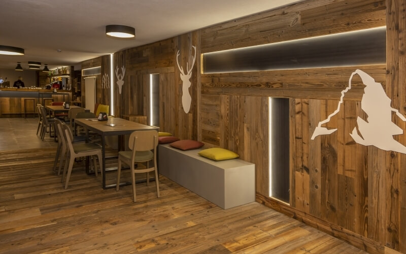 Cozy rustic restaurant with wooden walls, modern decor, natural light, and inviting seating areas for socializing.