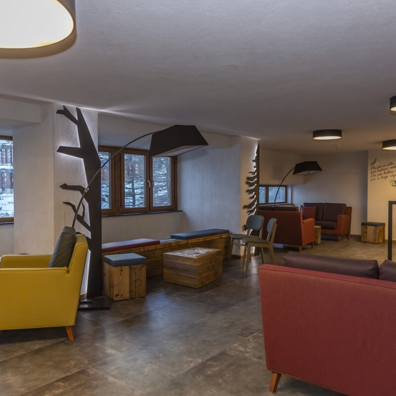 Modern seating area with diverse furniture, decorative plants, and multiple light fixtures, bathed in natural light.