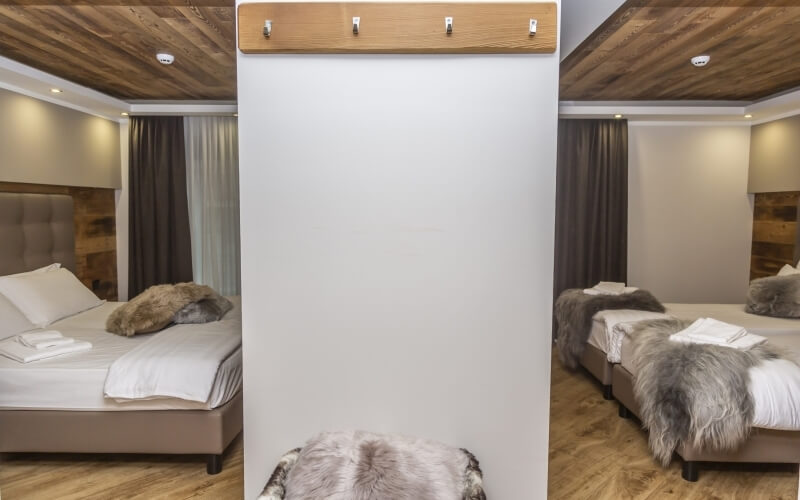 Collage of a hotel room: a coat rack, cozy beds with brown headboards, white linens, and a warm, inviting atmosphere.