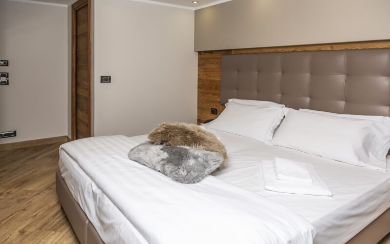 Serene hotel room with a plush king-size bed, gray and brown throw pillows, and a neatly folded white robe.