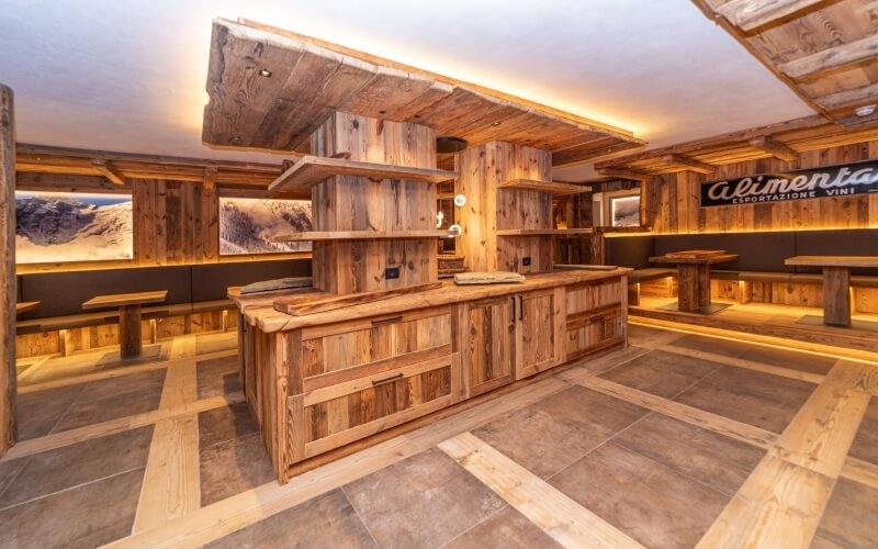 Interno di un bar rustico con un bancone in legno, insegna "alimenta" e atmosfera accogliente per mangiare e socializzare.