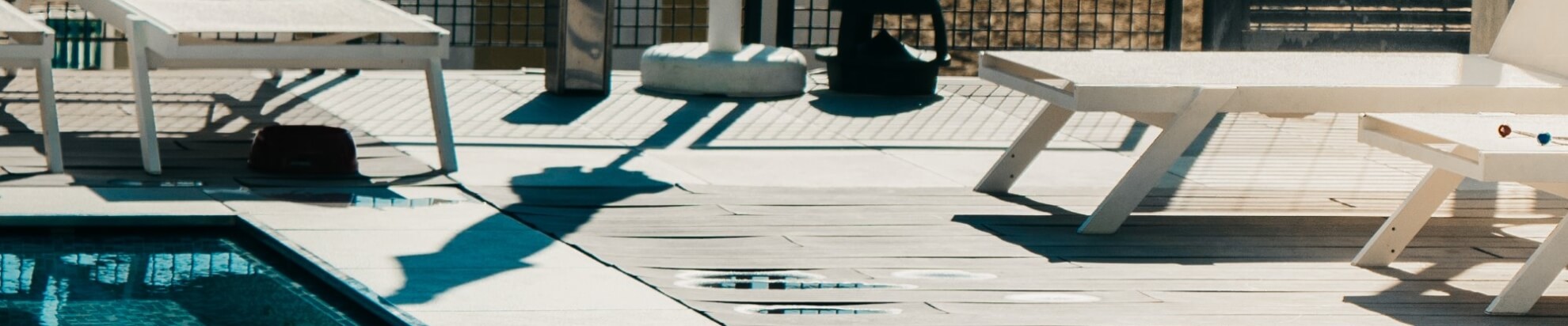 Impostazione all'aperto con piscina, sdraio bianche e luce calda, trasmettendo un'atmosfera di relax.