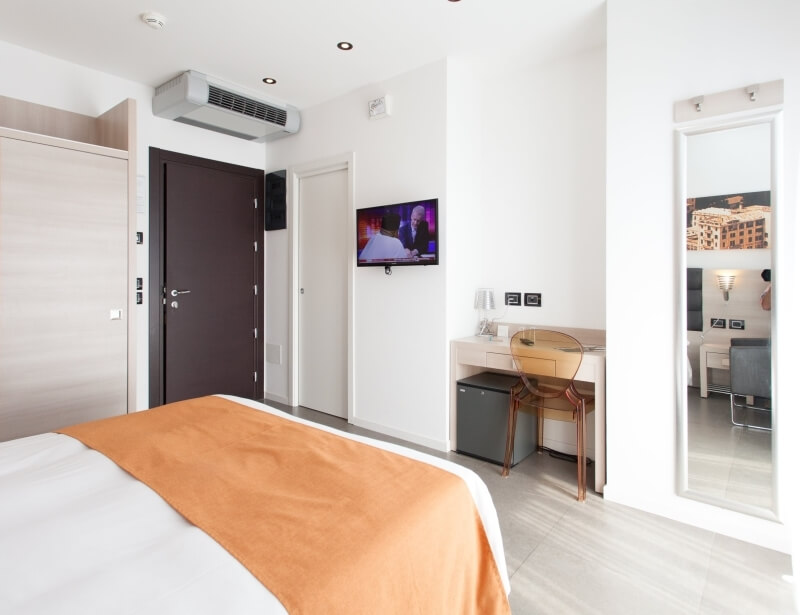 Ein einladendes Hotelzimmer mit einem Bett, Schreibtisch, Fernseher und großem Fenster, das viel natürliches Licht bietet.