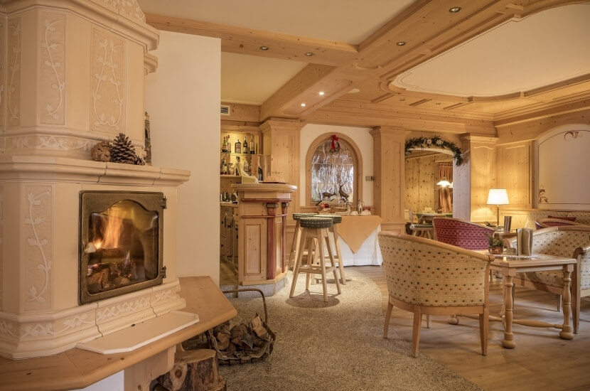 Gemütliches Wohnzimmer mit Kamin, Sitzbereich und Bar, warmes Ambiente, beige Wände und helle Holzakzente.