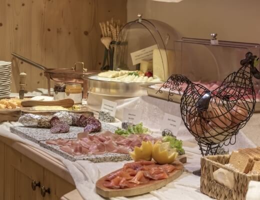 Buffet table with assorted meats, cheeses, pickled items, and decorative elements, set against beige walls.