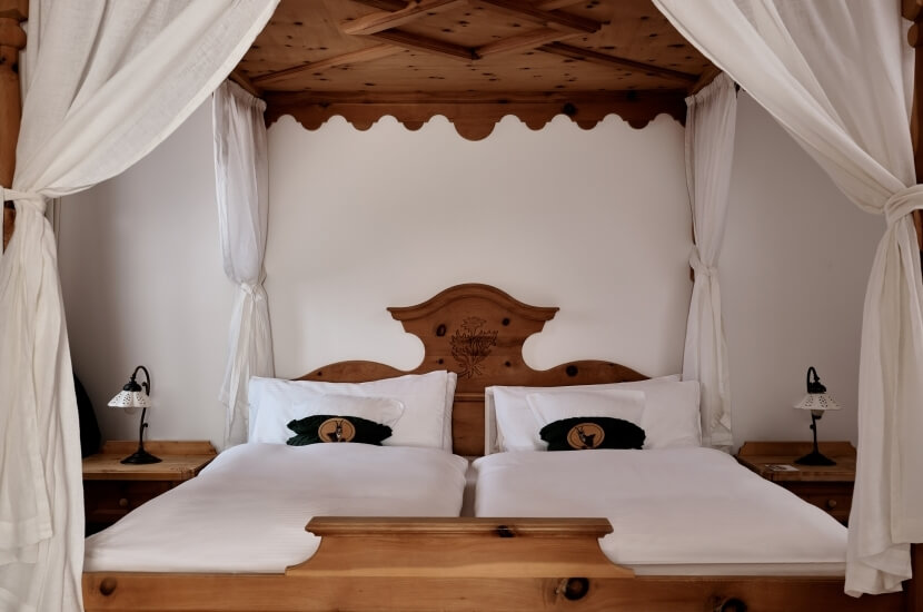 Camera da letto serena con letto matrimoniale, testiera decorata, lampade nere e tende bianche che creano un'atmosfera intima.