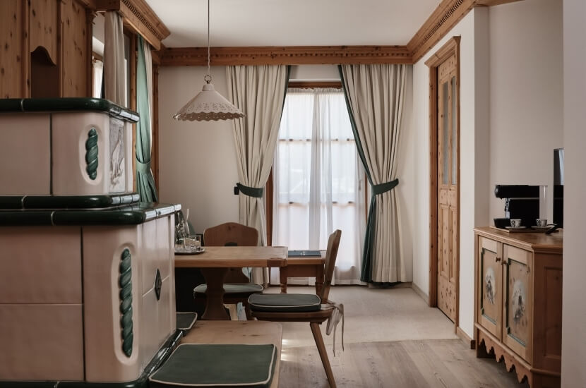 Una sala da pranzo accogliente con un tavolo, sedie, un forno beige e verde e una grande finestra con tende bianche.